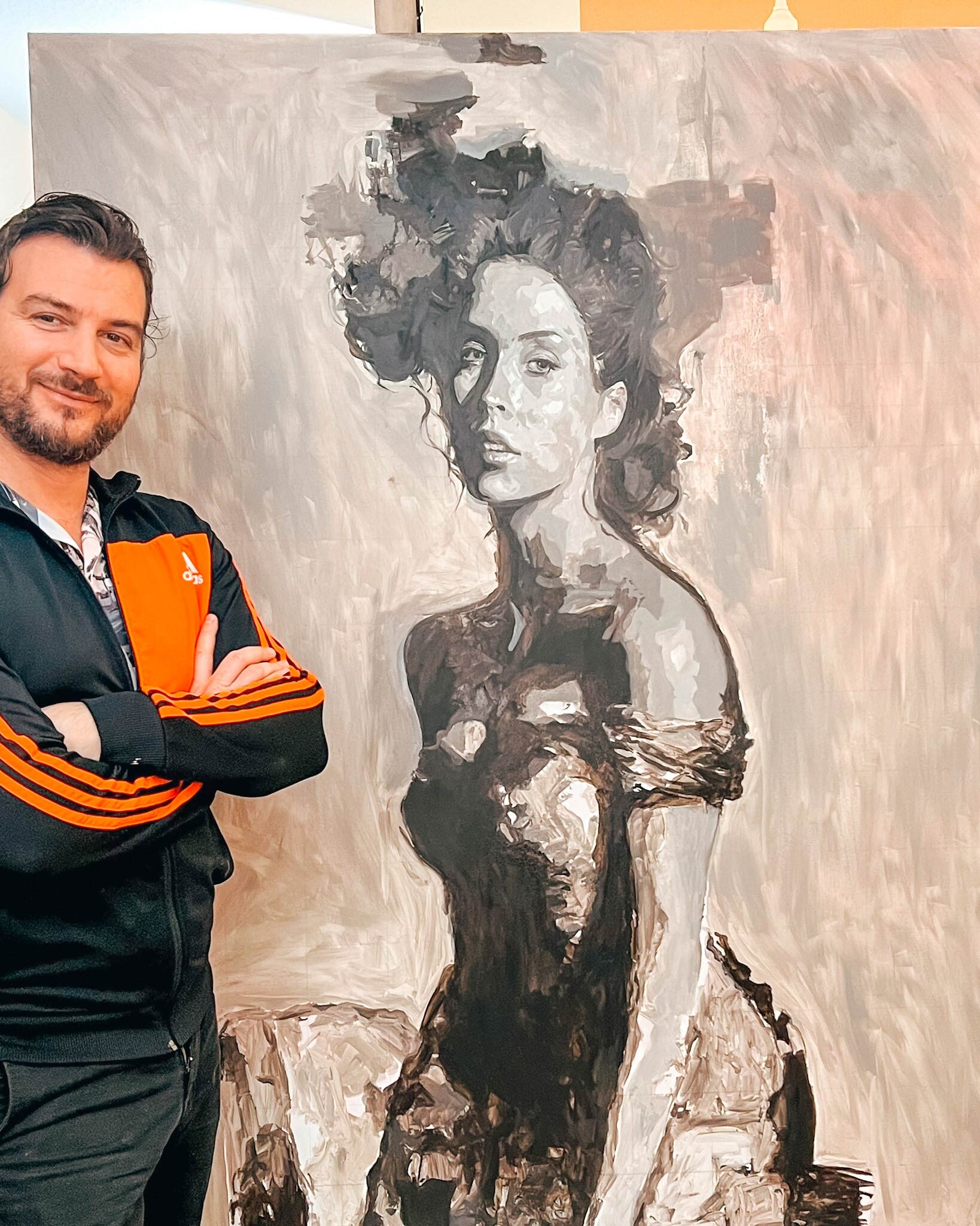 Artist standing next to a completed underpainting on a canvas