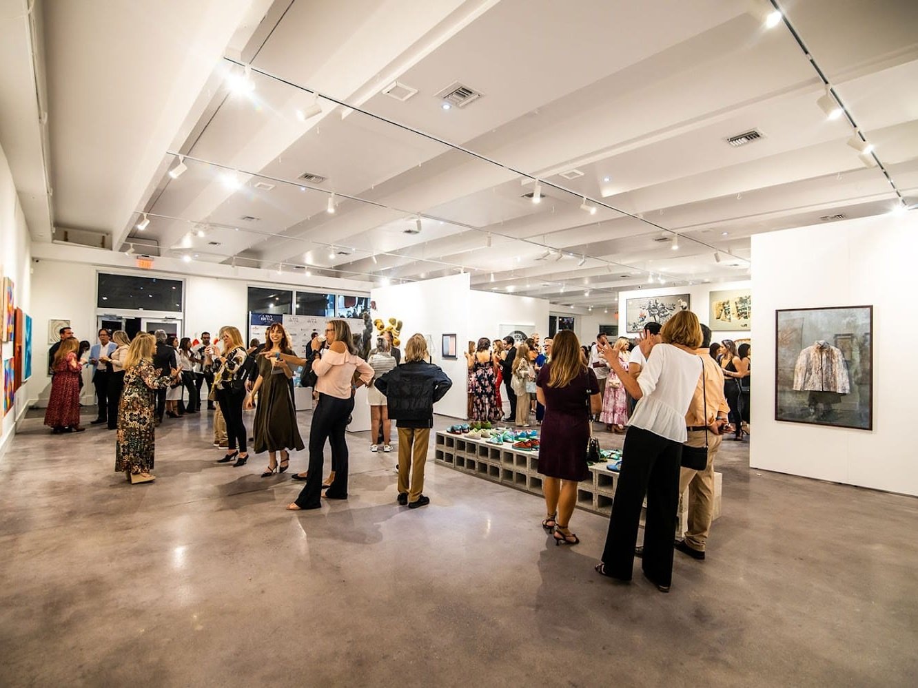 Miami Art Exhibits: Alex Righetto Solo Exhibition 9 A group of people are standing inside a gallery surrounded by artwork on display