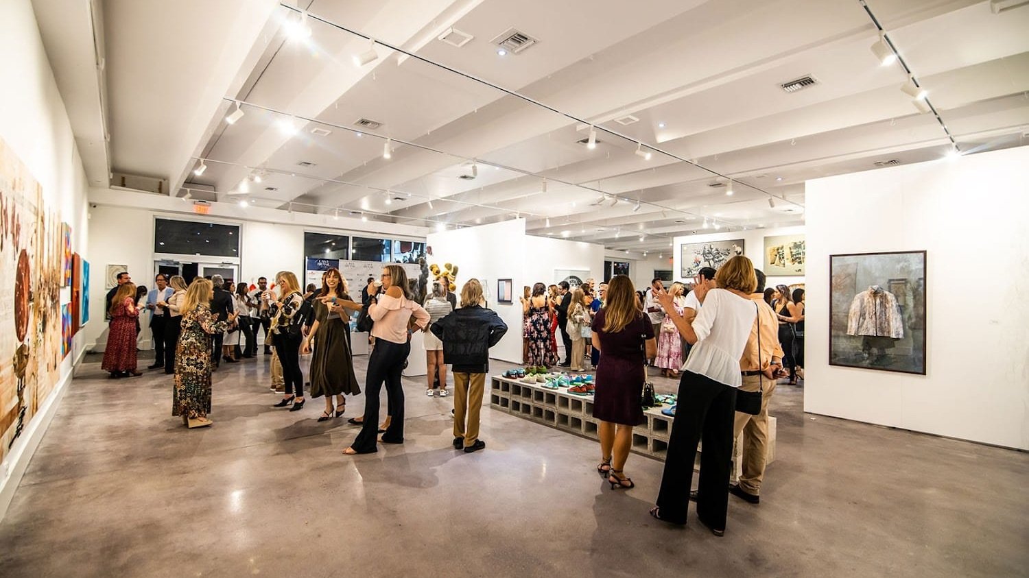 Miami Art Exhibits: Alex Righetto Solo Exhibition 3 A group of people are standing inside a gallery surrounded by artwork on display