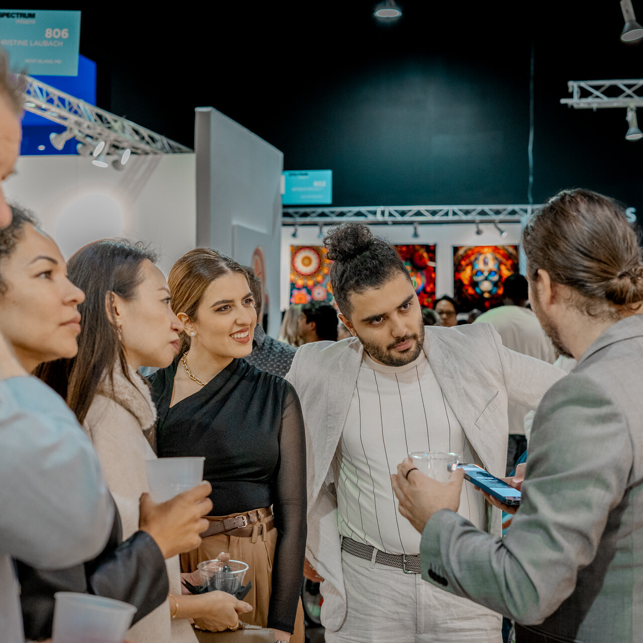 Alex Righetto in conversation with a group of attendees at the Spectrum Miami art fair, discussing his creative process.