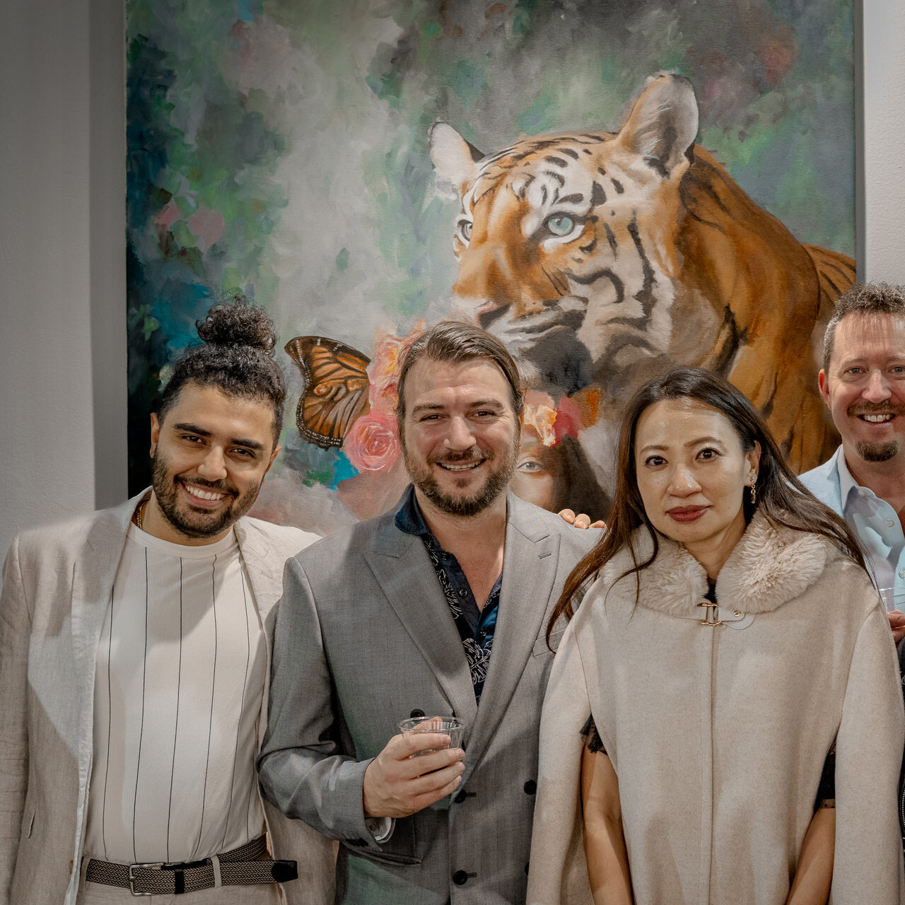 A group of happy art collectors pose with artist Alex Righetto at Spectrum Miami, with 'The Guardian' painting in the background.