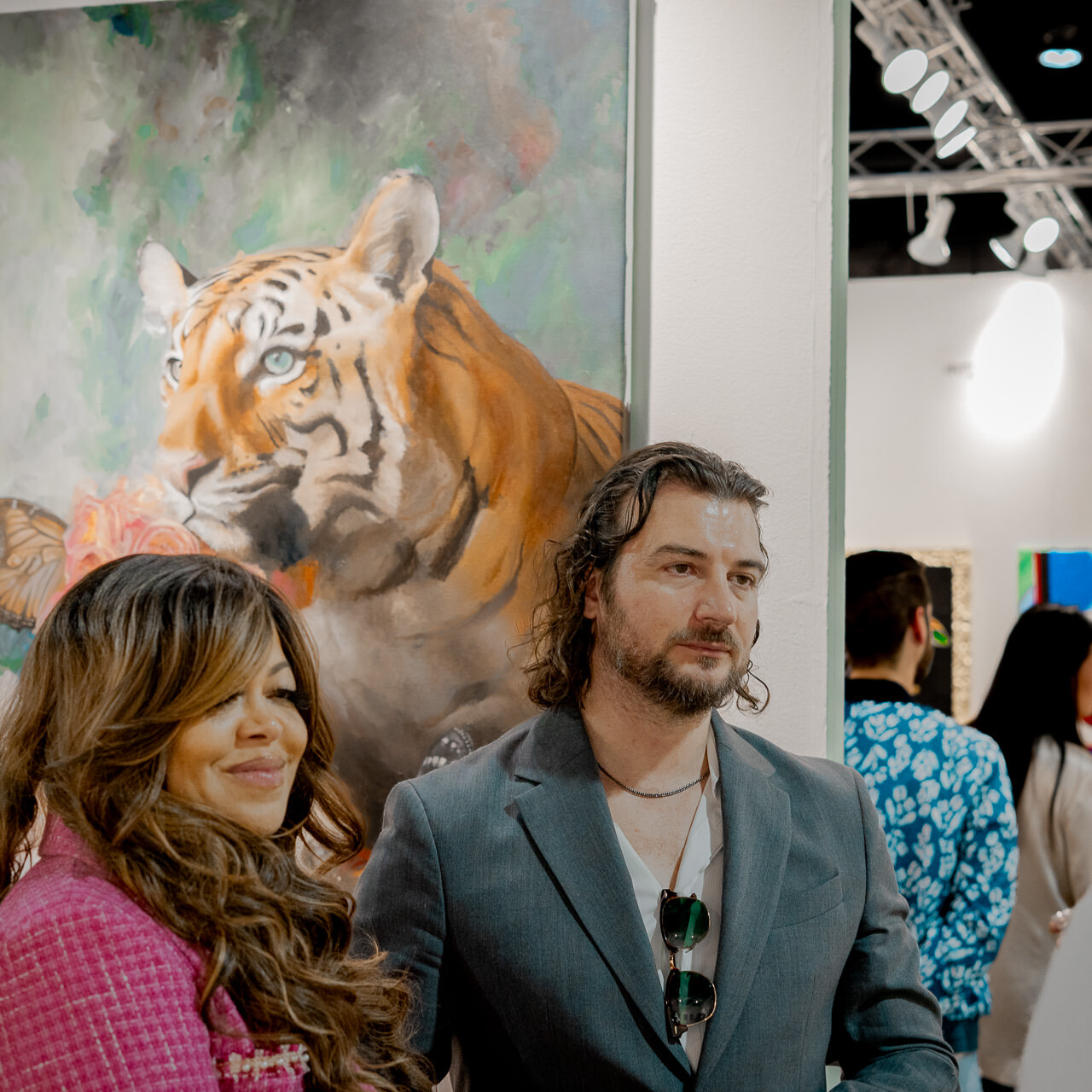 Stacy Francis and Alex Righetto attentively listen to art collectors at Miami Art Week, with Righetto's impactful painting 'The Guardian' enhancing the discussion.
