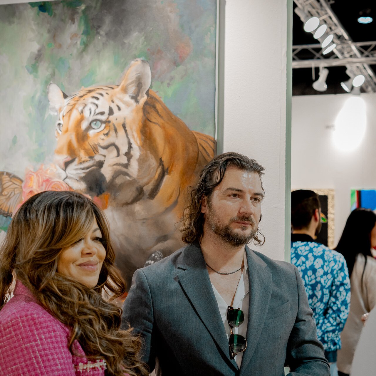 Stacy Francis and Alex Righetto attentively listen to art collectors at Miami Art Week, with Righetto's impactful painting 'The Guardian' enhancing the discussion.