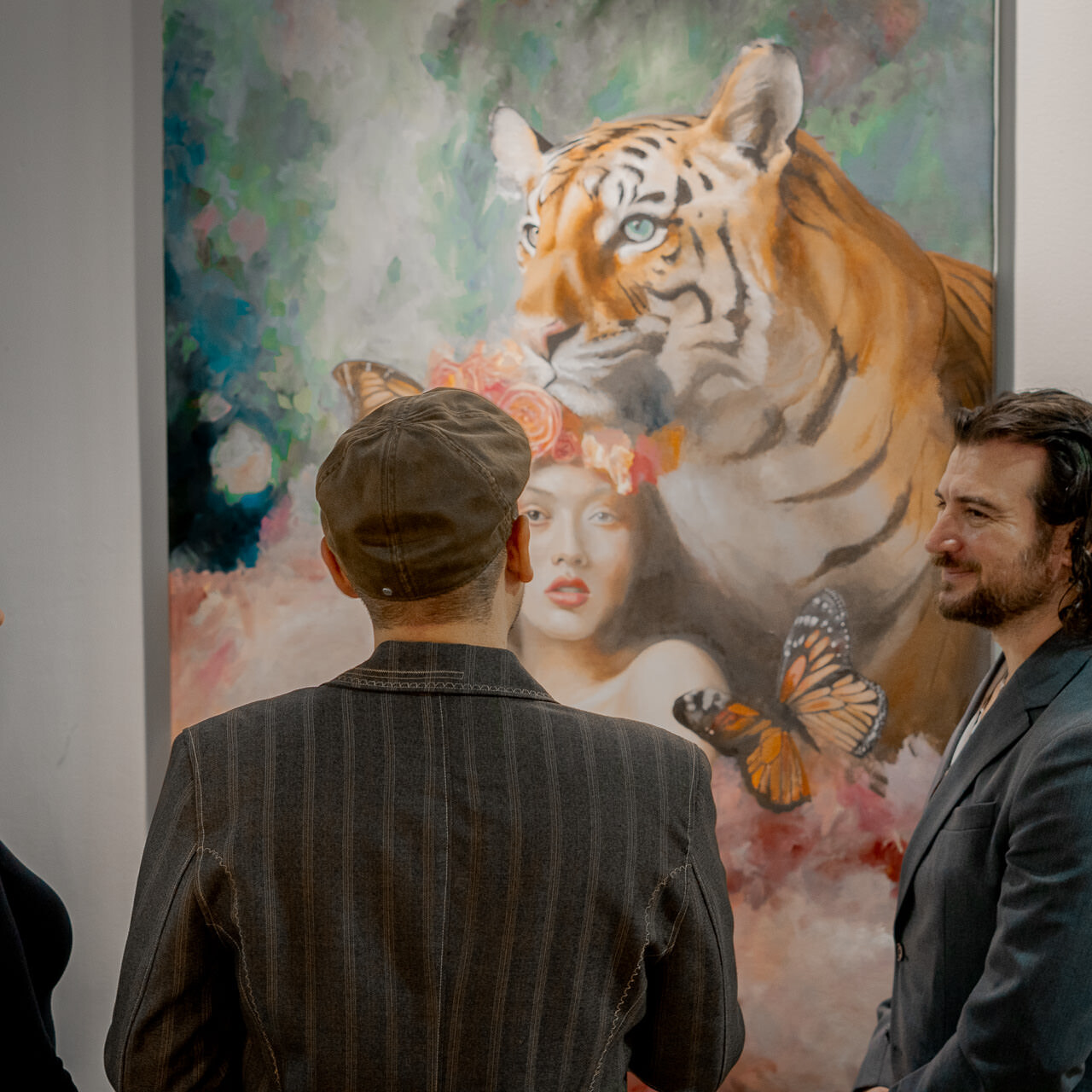 Alex Righetto converses with visitors at an art exhibition with 'The Guardian' in the background, illustrating the power of art to foster dialogue.