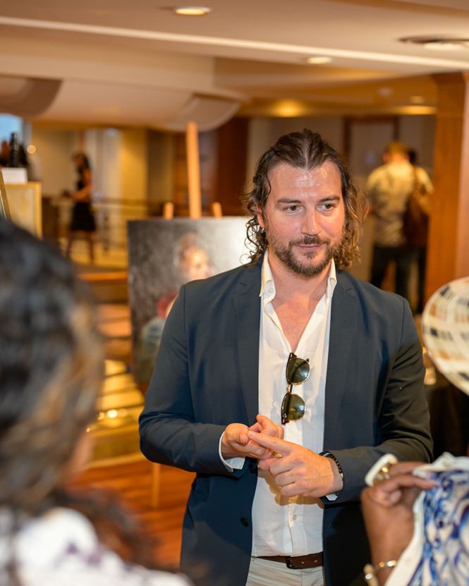 Alex Righetto in Conversation with a Collector 3 Alex Righetto speaking with a collector about his paintings during Art & Luxury Monaco 2026 at the Théâtre Princesse Grace in Monaco.
