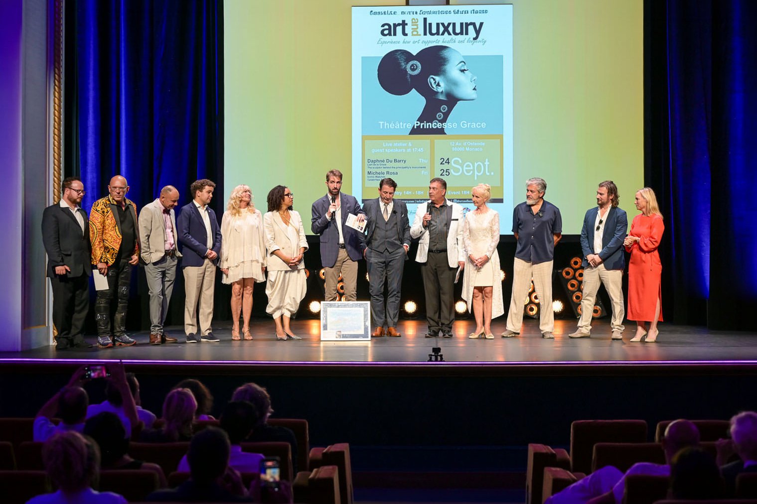 Alex Righetto on stage at Art & Luxury Monaco 2026 with Princess Margherita de Bourbon de Parme and event organizer Annette at the Théâtre Princesse Grace.